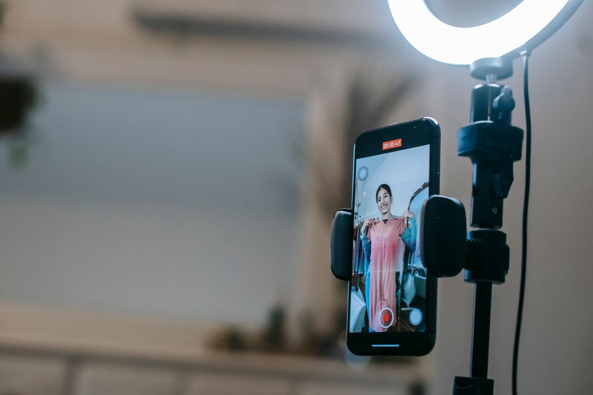 A creator posing in front of a ring light with a phone mounted in the center