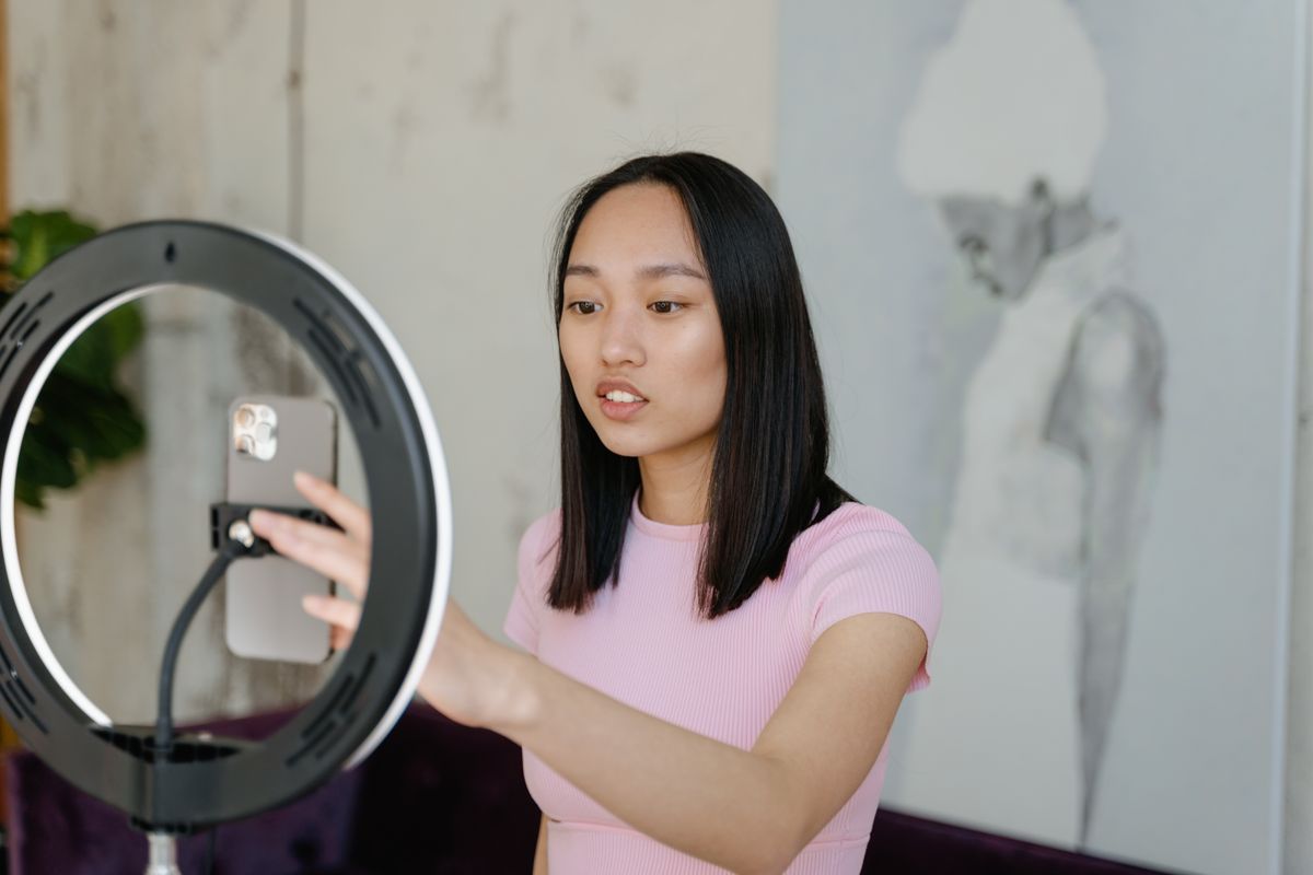 A creator posing in front of a ring light with a phone mounted in the center