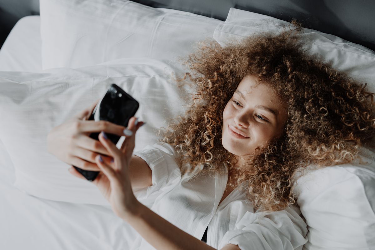 A creator managing messages and content on a phone at a bright desk